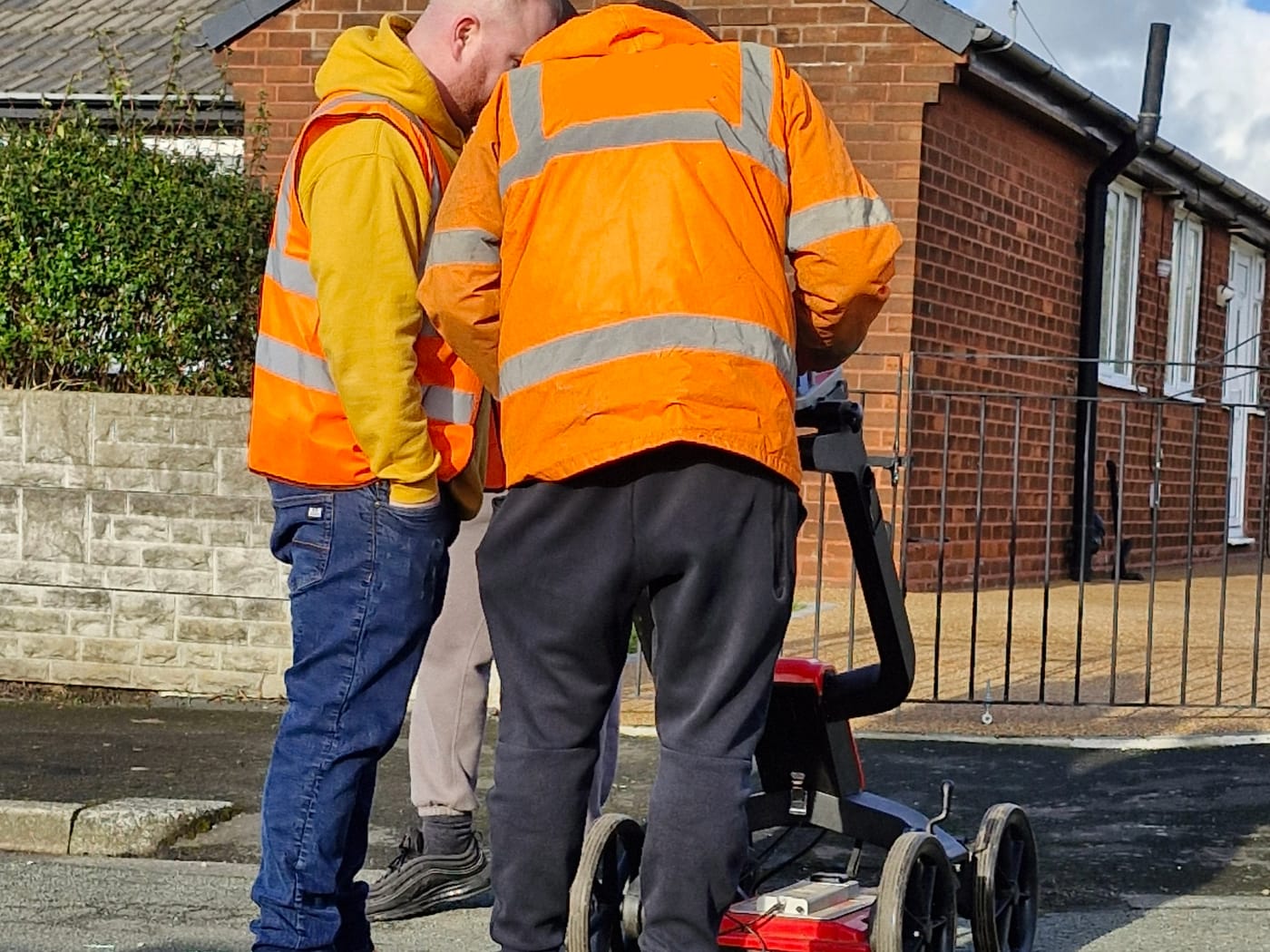 Delegates in hi-vis operating a utility GPR cart on a training course